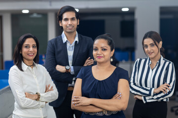 Confident Indian businesswoman standing infront of her office colleagues, selective focus, corporate environment, team members, business office.