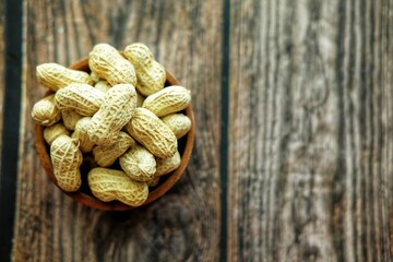 Peanuts on wooden bowl.