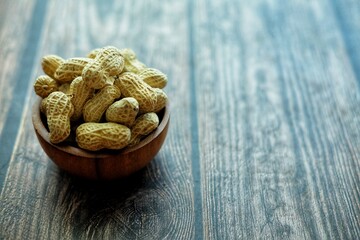 Peanuts on wooden bowl.