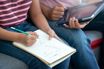 Close up, Asian boy doing math homework, dad nearby, educate at home