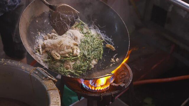 4K resolution super slow motion close up chef cooking Chinese style fried noodle in pan, street food at China town or Yaowarat, Bangkok Thailand