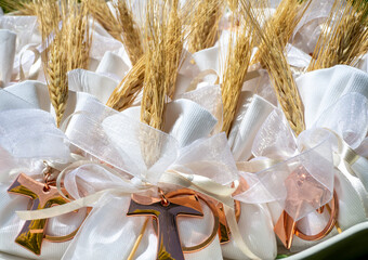 Gifts or favors for the first or holy communion. Small bags of white fabric with ear of wheat and Tau Christian cross. Religious symbol