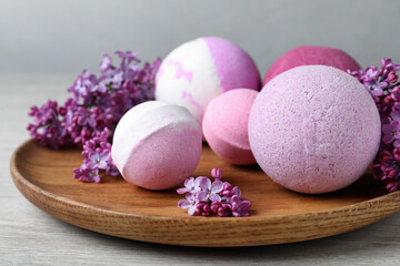Fragrant bath bombs and lilac flowers on wooden table, closeup