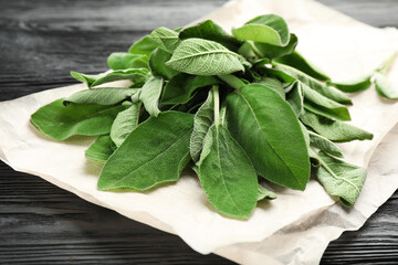 Bunch of fresh sage leaves on black wooden table, closeup