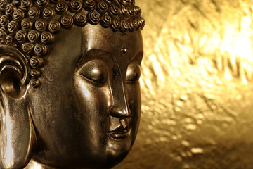 Buddha statue on golden background, closeup. Space for text