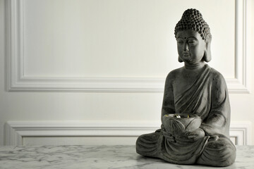 Buddha statue on white marble table. Space for text