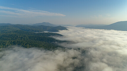 Aerial view: Mist or sea of fog cover the mountains valley. Cloudy view on top of a mount with clouds at foreground and background. ocean of clouds