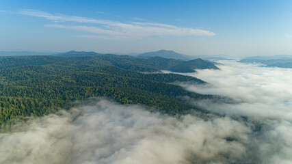 AERIAL view of Morning Mist. Mountain view morning of Top hill around with the ocean of mist with clouds moving in cloudy sky background. Mist over the mountaintop.
