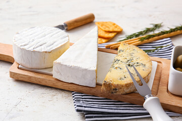 Board with tasty cheese and snacks on light background, closeup