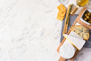 Board with tasty cheese, snacks and wine on light background