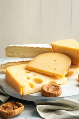 Tray with different types of cheese and dried figs on table, closeup