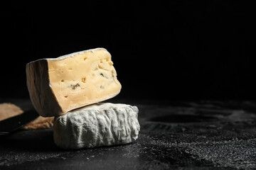 Pieces of tasty cheese on dark background, closeup