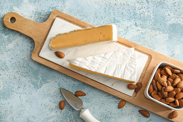 Fototapeta na wymiar Board with tasty cheese and almond nuts on color background