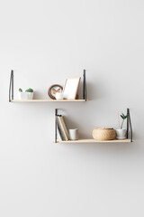 Modern shelves with decor hanging on light wall