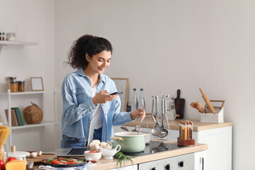 Young woman taking photo of tasty dish in kitchen