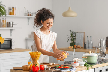 Young woman grating cheese on tasty pizza in kitchen