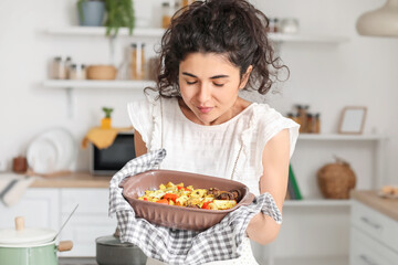 Young woman smelling tasty dish in kitchen