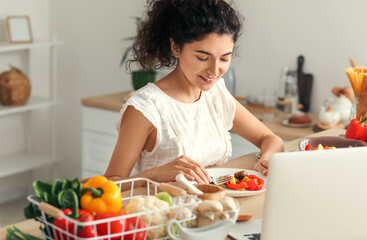 Obraz na płótnie Canvas Young woman eating tasty dish in kitchen