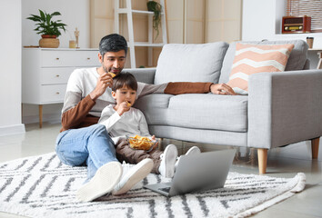 Father and little son watching movie at home