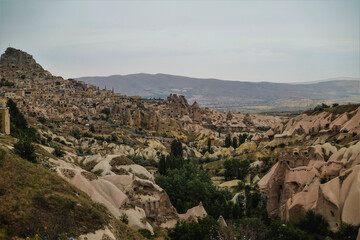 Fototapeta na wymiar The amazing landscape of Cappadocia. Unusual rocks with folded slopes, sharp peaks, caves. Rural houses on the mountainside. Pigeon Valley. Turkey