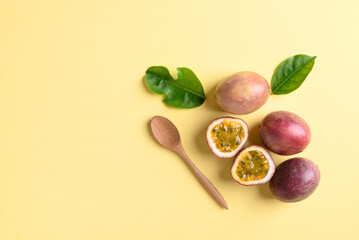 Fresh passion fruit with wooden spoon on yellow background