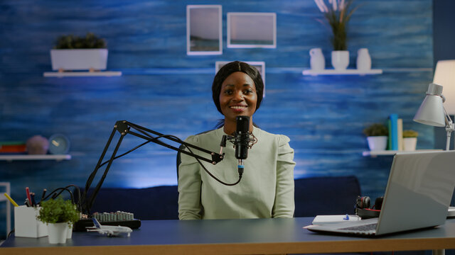 Portrait of african vlogger working in cozy studio, smiling at camera ready to start new podcast show. On-air online production internet broadcast show host streaming web content record digital blog