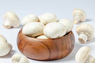 Fresh white champignons in brown bowl on white background.