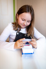 pretty young schoolgirl sitting on her desk in her room at home learning english vocabulary using...