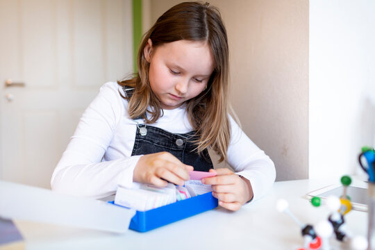 pretty young schoolgirl sitting on her desk in her room at home learning english vocabulary using flashcards during corona time