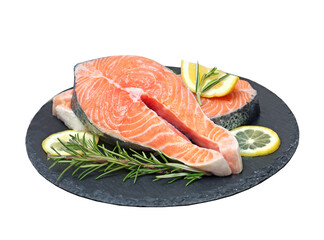Salmon fresh fish steak served with lemon and herbs on slate isolated on white.