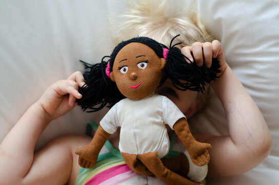 Little gilr plays with different skin color doll