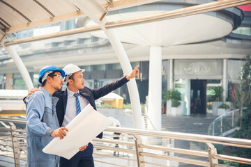 Civil engineer teams meeting working together wear worker helmets hardhat on construction site in modern city. Foreman industry project manager engineer teamwork. Asian industry professional team