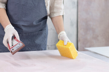 The girl treats the surface of a sheet of plywood and paints on it with spray paint. Space for the...