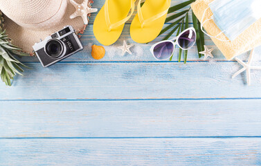 Summer holiday, travel and vacation concept. Sunglasses, starfish, beach hat, flip flop, seashell and medical mask to protect covid-19 on pastel blue wooden background.