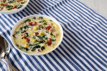 Homemade Zuppa Toscana with Kale and Bread in a white bowl, side view. Copy space.