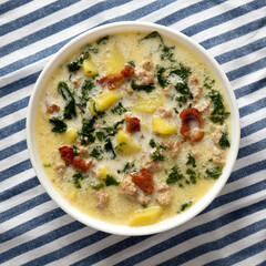 Homemade Zuppa Toscana with Kale and Bread in a white bowl, top view. Flat lay, overhead, from above. Copy space.