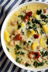 Homemade Zuppa Toscana with Kale and Bread in a white bowl, top view. Flat lay, overhead, from above. Close-up.