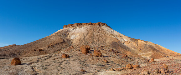 Panoramic view of a flat top mesa in The Breakaways South Australia showing the rocks that have been eroded from the top and rolled to the base