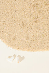 Doll's sunlit shoes and traces of shoes in the sand made of African ancient cereal fonio millet whole grain on a pastel beige background. Minimal natural flat lay concept with copy space.