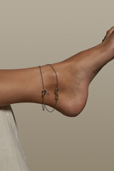 Cropped shot of female bare foot in the air. The ankle is adorned with silver anklet made as...