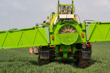 Traktor mit Feldspritze beim Ausbringen von Pflanzenschutzmittel gegen Pestizid