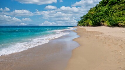 A picturesque beach scene with turquoise water, ebbing tide, wet sand, fluffy clouds, and no people. Shot in Abra de Ilog, Mindoro Island, Philippines.