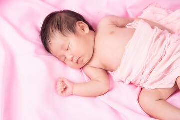 Portrait of a one month old sleeping, newborn baby girl on a pink blanket. Concept portrait studio fashion newborn.