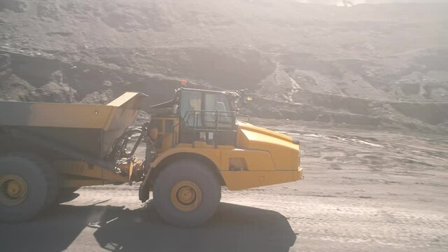 Large quarry dump truck. Loading rock in dumper. Loading coal into truck. Mining car machinery to transport coal. Open pit mine quarrying extractive industry stripping work. Big Yellow Mining Trucks