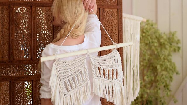 Attractive blonde woman demonstrates home decor made in the macrame technique.Slow motion.