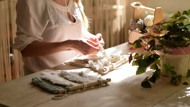 Close up of women's hands weaving macrame in a home workshop.Handmade concept.Slow motion.