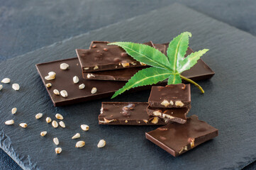 Marijuana leaves and dark chocolate on black background