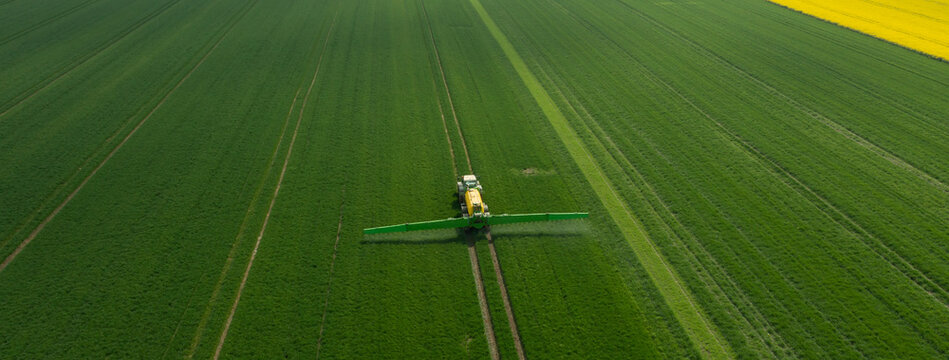 Traktor mit Feldspritze beim Ausbringen von Pflanzenschutzmittel gegen Pestizid