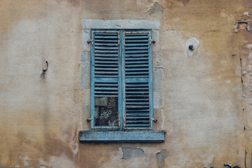 Fototapeta na wymiar Une vieille fenêtre fermée. Des vieux volets en bois fermés et abimés. Des volets usés.