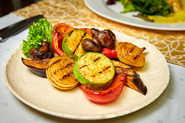 Plate with grilled vegetables. Zucchini, mushrooms, eggplant, bell pepper, onion. Close-up, selective focus